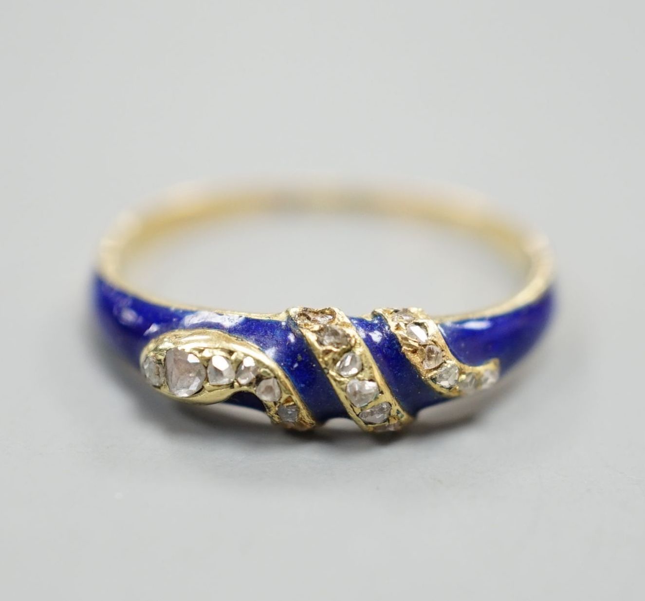 A late Victorian yellow metal, blue enamel and rose cut diamond set serpent ring, size O, gross weight 2.5 grams.